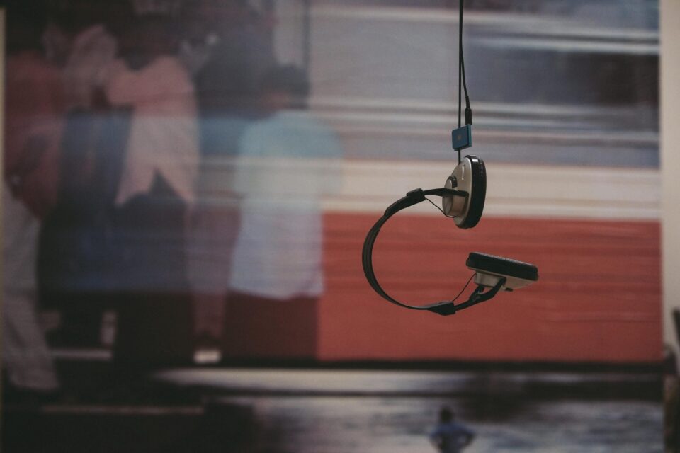 Weather Station – Brendan Buesnel Headphones hanging from a cord in front of a blurred poster