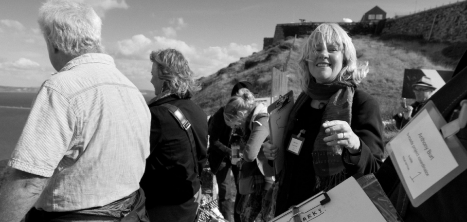 A group of people with clipboards looking out over Portland, a woman with blonde hair smiles into the camera